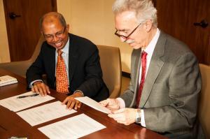 2 men signing papers to initiate the chowdry center