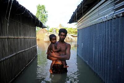 man holding a baby while wading in water